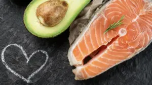 Trancio di salmone crudo accanto a mezzo avocado su sfondo scuro