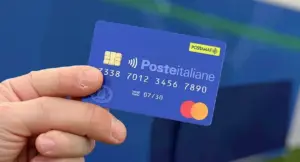 Una mano tiene una carta prepagata Poste Italiane con logo Mastercard