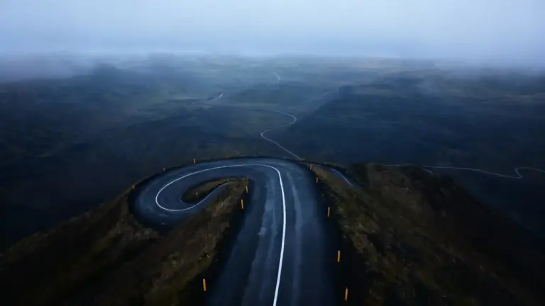 Strada deserta che si snoda tra le montagne sotto un cielo nebbioso