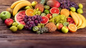 Varietà di frutta fresca su un tavolo di legno, tra cui uva, ananas, kiwi e agrumi