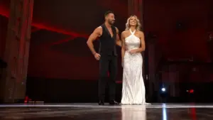 Due persone su un palco durante un'esibizione di danza, con scenografia illuminata di rosso