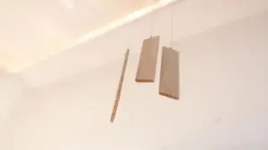 Tre pannelli di legno sospesi in aria in uno spazio neutro