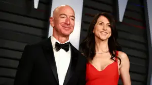 Una donna in abito rosso accanto a un uomo in smoking, sorridenti su un red carpet