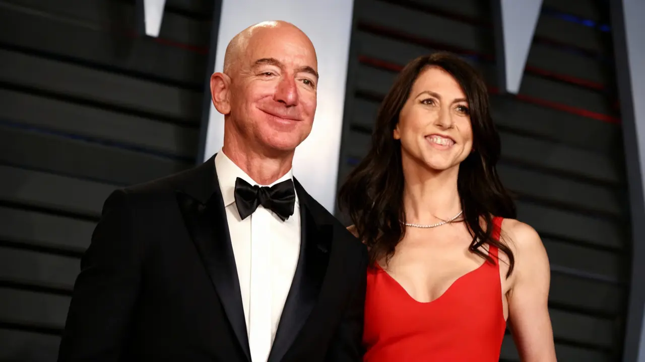 Una donna in abito rosso accanto a un uomo in smoking, sorridenti su un red carpet