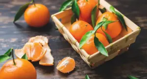 Cestino con mandarini freschi e spicchi su tavolo in legno scuro