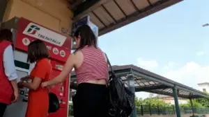 Persone utilizzano una biglietteria automatica Trenitalia in una stazione ferroviaria all’aperto