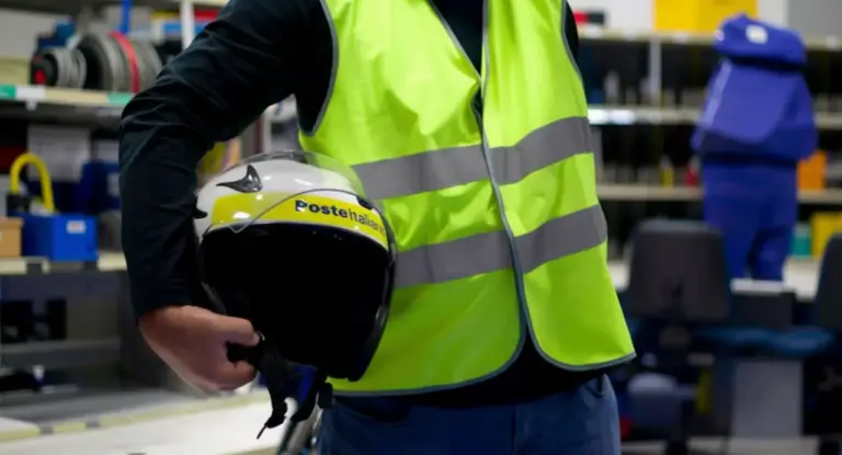 Persona con giubbotto riflettente che tiene in mano un casco Poste Italiane