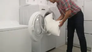 Persona che inserisce un cuscino in lavatrice in una lavanderia domestica