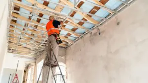 Persona su una scala che lavora alla ristrutturazione del soffitto di un edificio