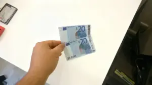 Una mano tiene due banconote da 20 euro sopra un tavolo bianco