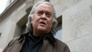 Una persona con capelli grigi davanti a un edificio in pietra chiara