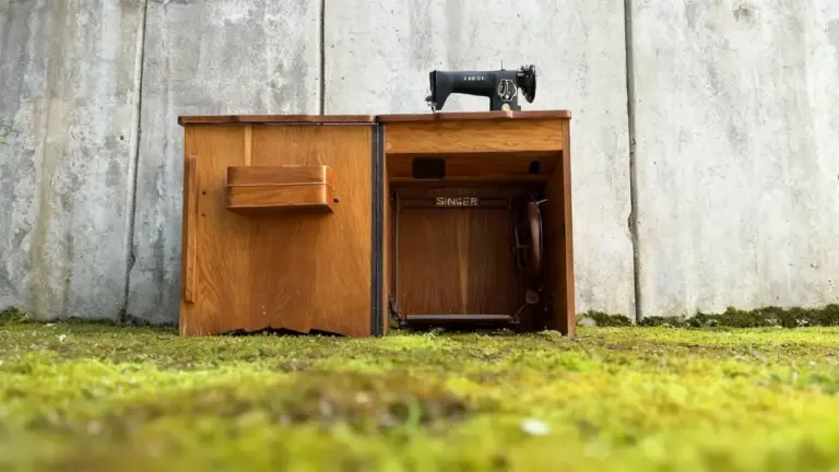 Macchina da cucire Singer del 1970 con mobiletto in legno su sfondo in cemento
