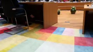 Sala riunioni con tavoli in legno e moquette colorata durante un incontro ufficiale
