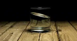 Bicchiere d'acqua su una superficie di legno in un ambiente scuro