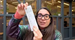 Una persona mostra uno scontrino davanti a un locale a Milano