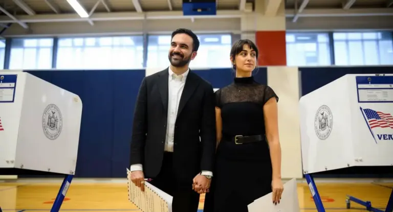 Due persone tengono schede elettorali tra cabine di voto a New York