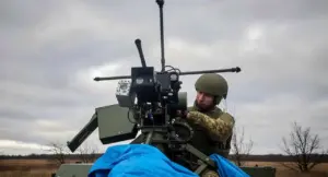 Soldato in uniforme mimetica lavora su un sistema di armamento montato su veicolo militare