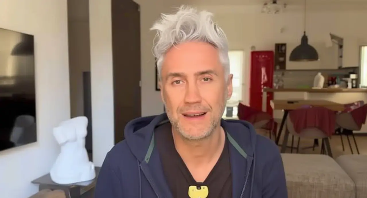 Persona con capelli grigi seduta in un soggiorno moderno che guarda verso la fotocamera