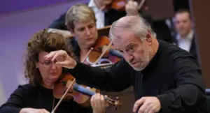 Un direttore d'orchestra conduce un gruppo di musicisti con violini durante un'esibizione.