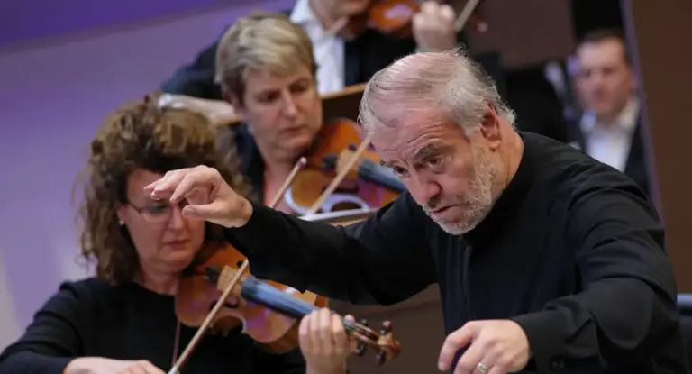 Un direttore d'orchestra conduce un gruppo di musicisti con violini durante un'esibizione.