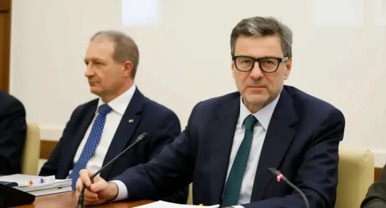 Due uomini in abiti formali siedono a un tavolo durante una riunione istituzionale