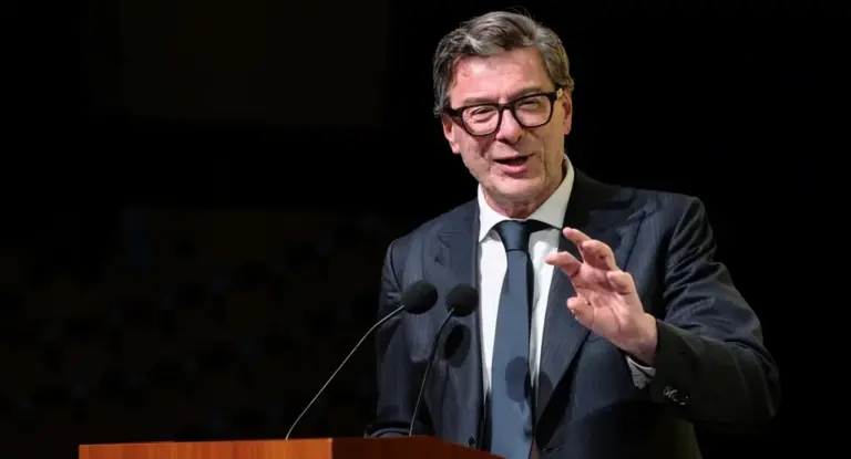 Un uomo in abito parla da un podio con due microfoni