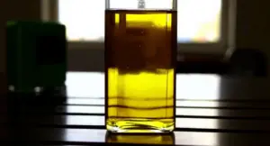 Bottiglia di vetro con olio di oliva su un tavolo alla luce del sole