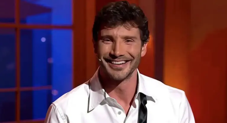 Un uomo sorride in uno studio televisivo illuminato