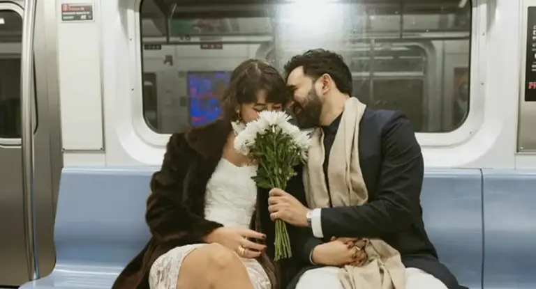 Una coppia abbracciata su un vagone della metropolitana, con un mazzo di fiori bianchi