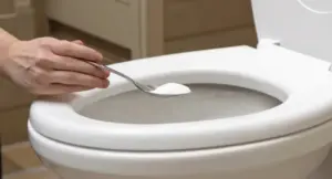 Una mano versa una sostanza bianca in polvere nel water con un cucchiaio