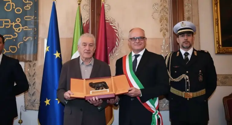 Una persona riceve un riconoscimento cerimoniale accanto a rappresentanti istituzionali a Roma