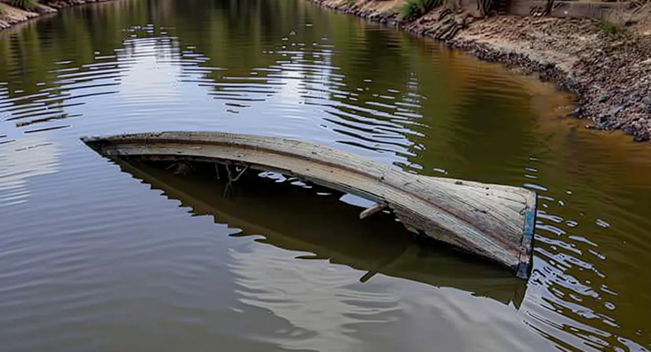 Barca semi sommersa in acqua torbida vicino a una riva fangosa