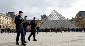 Agenti di polizia pattugliano l'esterno di un museo con una piramide di vetro